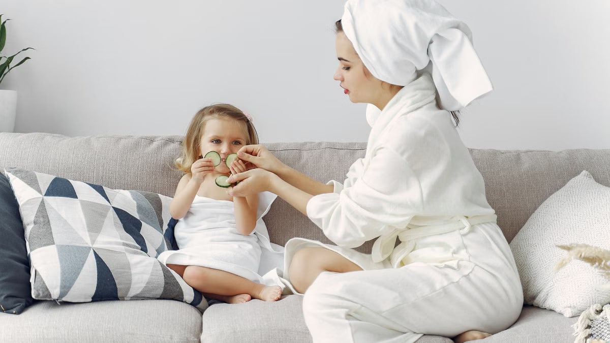 A mother and daughter enjoy a spa day at home, bonding on the couch with cucumber slices.